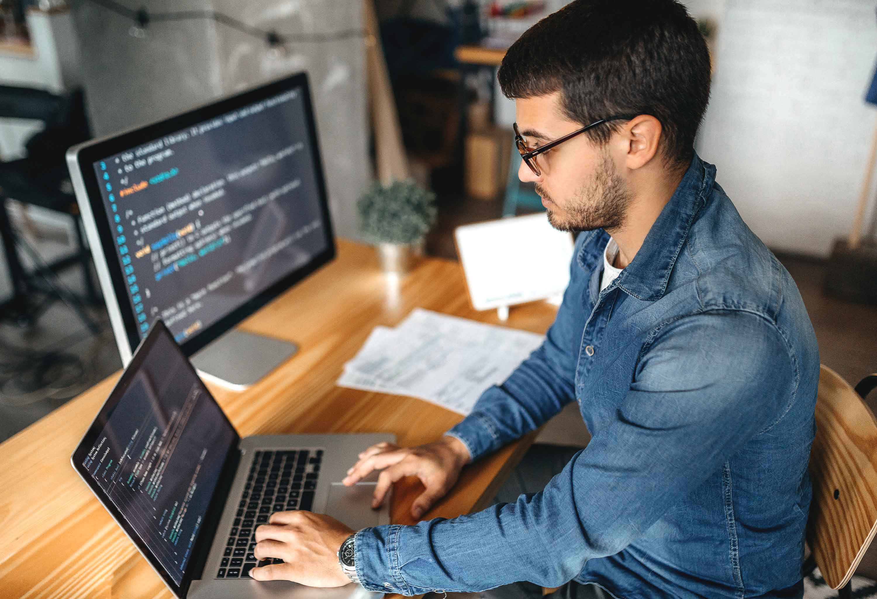 A man with specs is looking into his laptop and working