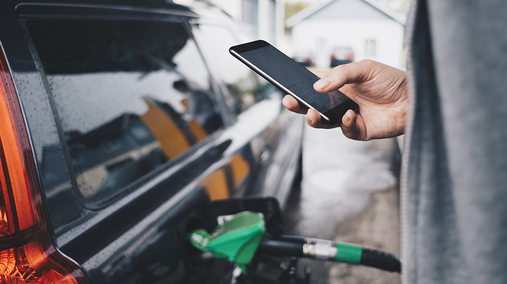 Scrolling on phone at gas pump